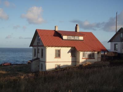 Photo of white cottage with red roof.